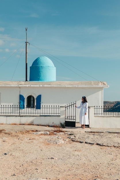 Hermosa mujer con vestido blanco cerca de la antigua iglesia de Grecia