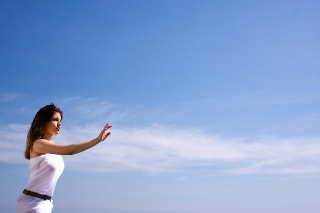 Hermosa mujer en vestido blanco y cielo azul