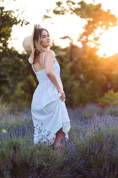 Hermosa mujer con vestido blanco largo y percheros en Prado de lavanda en la hora dorada