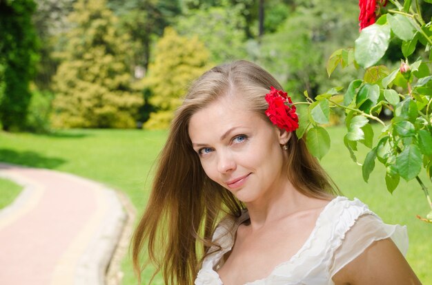 Hermosa mujer en vestido blanco entre las plantas en el parque