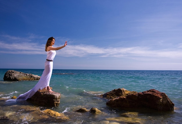 Hermosa mujer con vestido blanco en la playa del mar