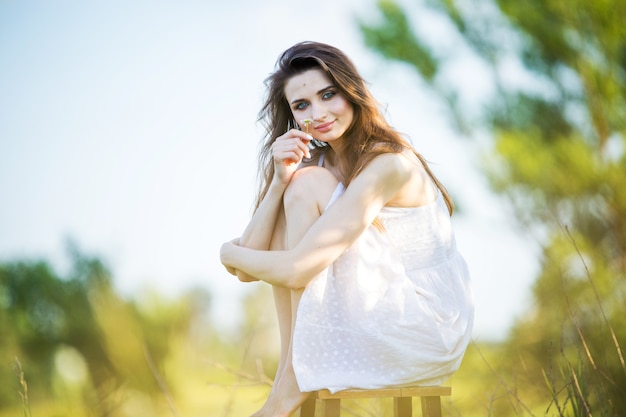 Hermosa mujer con un vestido blanco en una silla