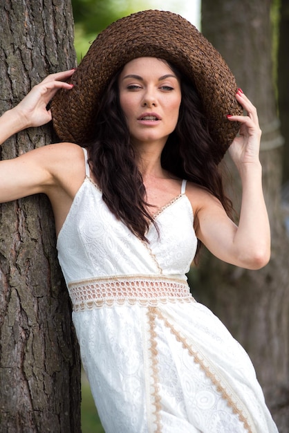 Hermosa mujer con vestido blanco de verano y sombrero de paja