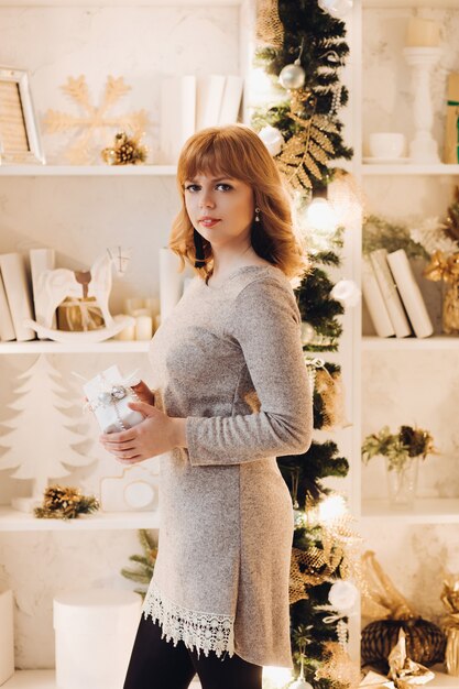 Hermosa mujer en vestido gris con regalo de Navidad.