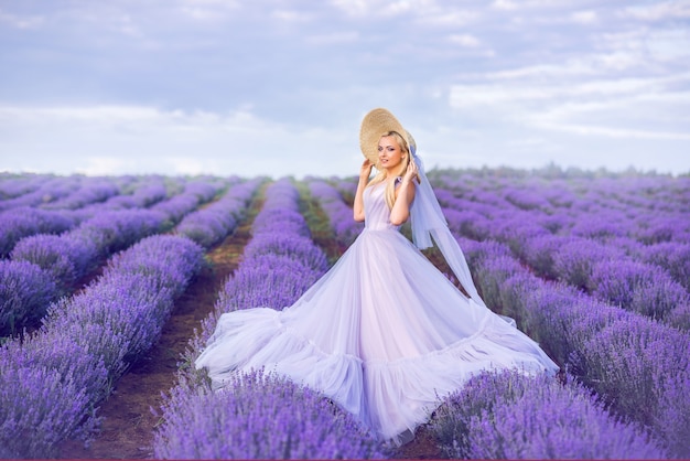 Hermosa mujer con un vestido largo morado sobre un fondo de lavanda. Una niña en forma de hada y ninfa de flores.