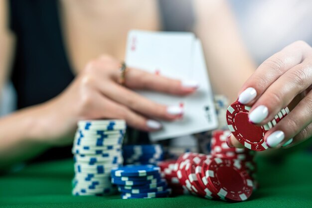 Hermosa mujer con un vestido negro de noche juega al póquer en un casino en una mesa verde