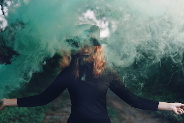 Foto hermosa mujer en vestido negro de pie en el bosque.