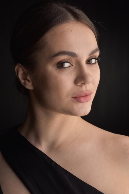 Hermosa mujer en vestido negro sobre fondo negro