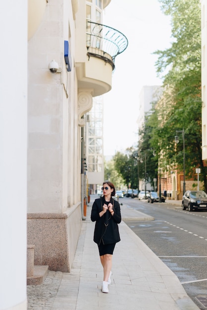 Hermosa mujer con un vestido negro sobre un fondo de un paisaje urbano