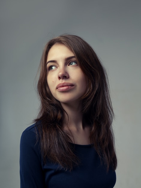 Hermosa mujer en un vestido negro sobre gris