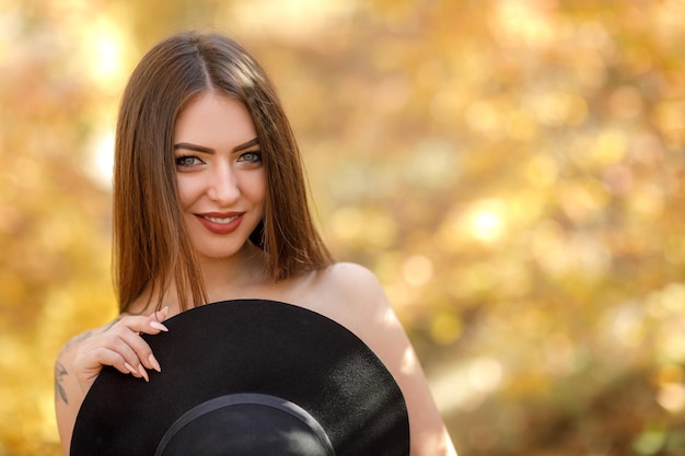 Hermosa mujer con vestido negro y sombrero en otoño