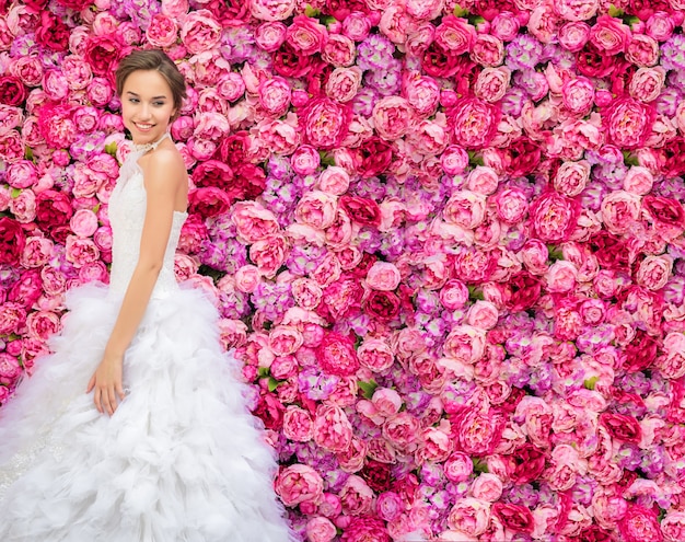 Hermosa mujer en un vestido de novia en una pared floral