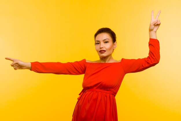 Hermosa mujer en vestido rojo dedo acusador sobre fondo amarillo