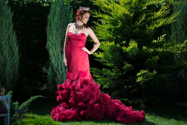 Hermosa mujer con un vestido rojo en el jardín.