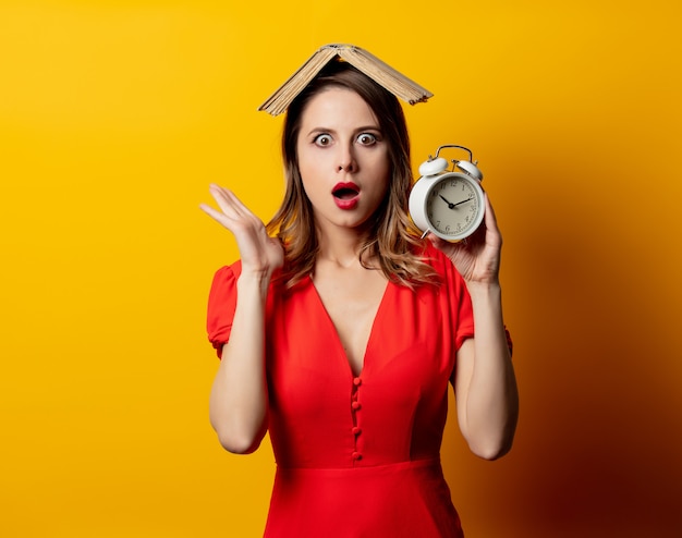 Hermosa mujer en vestido rojo con reloj despertador