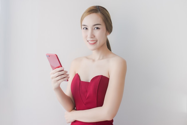 Hermosa mujer en vestido rojo usa teléfono rojo en casa