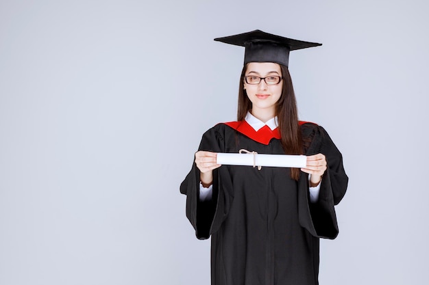 Hermosa mujer en vestido sosteniendo su diploma universitario. Foto de alta calidad