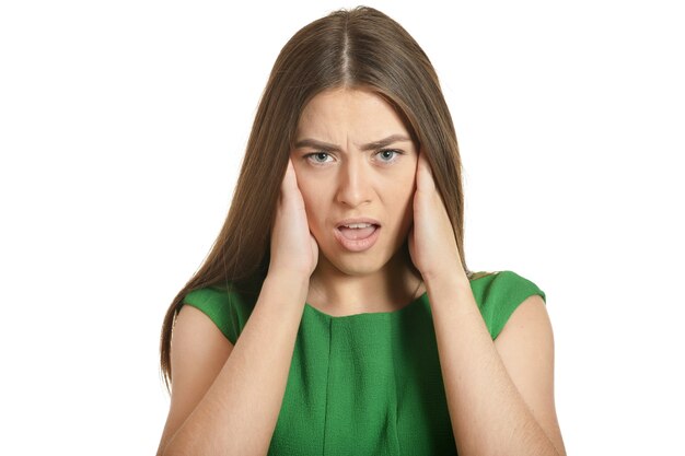 Hermosa mujer en vestido verde con dolor de cabeza sobre fondo blanco.