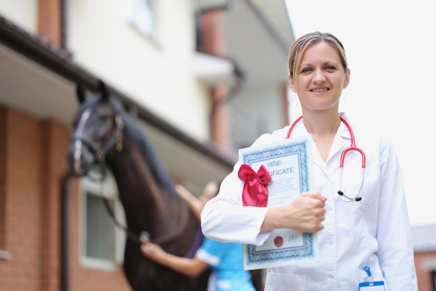 Hermosa mujer veterinaria tiene certificado médico al lado del caballo