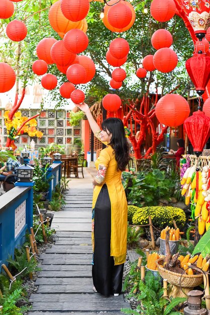 Hermosa mujer vietnamita con vestido vietnamita tradicional cerca de farolillos rojos en el Año Nuevo Lunar Tet