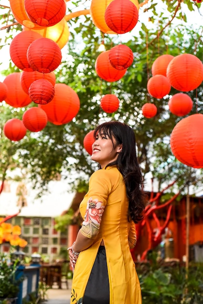 Foto hermosa mujer vietnamita con vestido vietnamita tradicional cerca de farolillos rojos en el año nuevo lunar tet