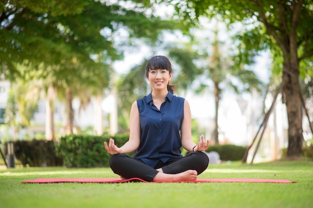 Hermosa mujer de yoga en el parque verde