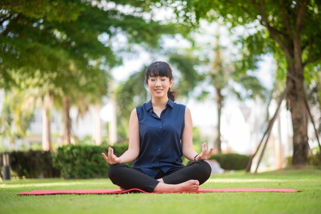 Hermosa mujer de yoga en el parque verde