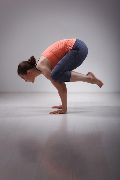 Foto hermosa mujer yogini en forma deportiva que practica el yoga asana kakasana