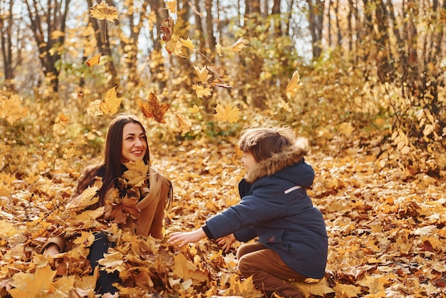 Hermosa naturaleza Madre con su hijo se divierte al aire libre en el bosque de otoño