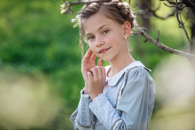 Hermosa niña de 6-7 años posando en el jardín. Tiempo de Pascua. disfruta de la primavera y el calor. Hermoso jardín de primavera. Concepto de infancia, paz y felicidad feliz. Flor aromática y retro vintage.