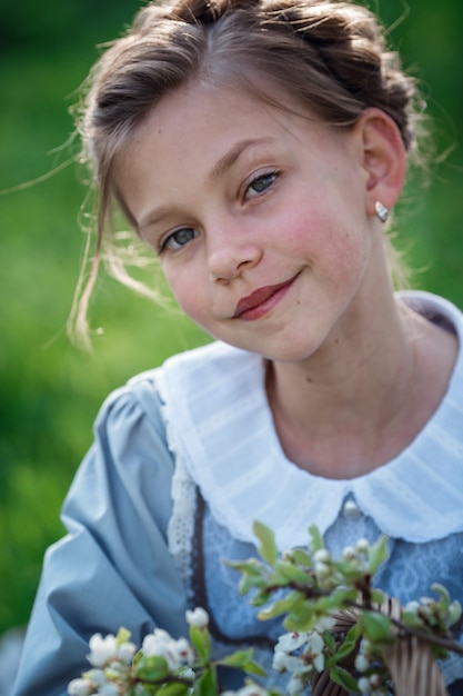 Hermosa niña de 6-7 años posando en el jardín. Tiempo de Pascua. disfruta de la primavera y el calor. Hermoso jardín de primavera. Concepto de infancia, paz y felicidad feliz. Flor aromática y retro vintage.