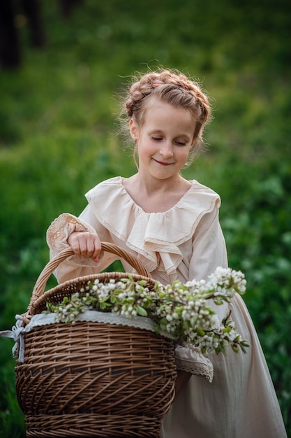 Hermosa niña de 6-7 años posando en el jardín con vestido blanco. Tiempo de Pascua. disfruta de la primavera y el calor. Concepto de infancia, paz y felicidad feliz. Flor aromática y retro vintage.