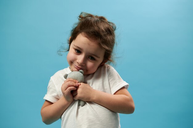 Hermosa niña abraza a su juguete y mirando hacia abajo con tristeza