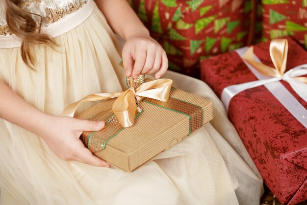 Hermosa niña abriendo una caja de regalo de Navidad. Celebración de Navidad y año nuevo.