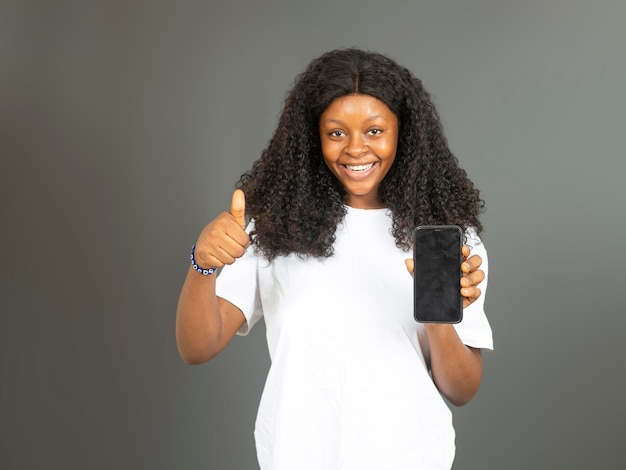 Hermosa niña africana emocionada sosteniendo un teléfono móvil