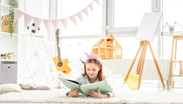 Hermosa niña con álbum de fotos tirado en el piso en una acogedora habitación