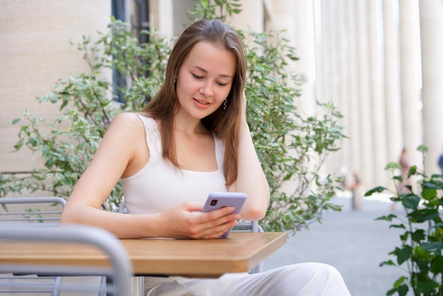 hermosa niña alegre mujer joven en un café usando su teléfono inteligente teléfono móvil chateando escribiendo