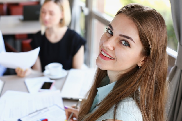 Hermosa niña alegre sonriente en el lugar de trabajo