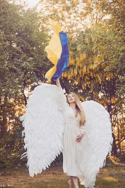 Hermosa niña ángel en el jardín nocturno con bandera ucraniana