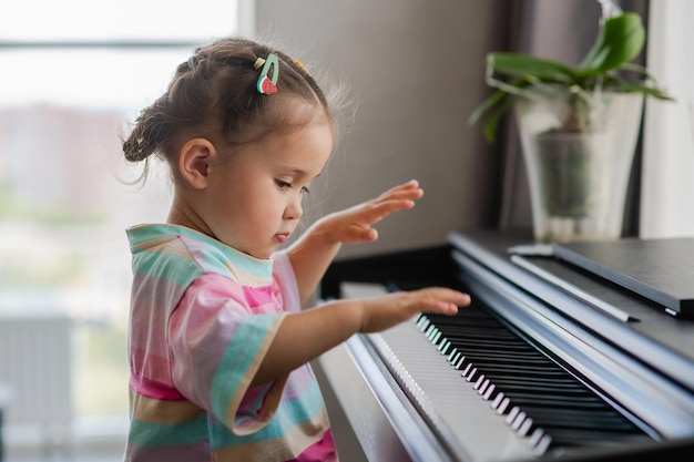 Una hermosa niña asiática toca el piano en la sala de estar o en la escuela de música