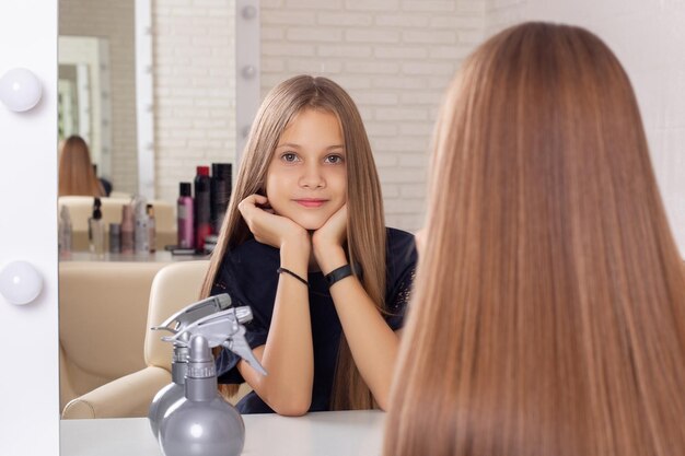 Hermosa niña con cabello moreno largo y saludable en peluquería