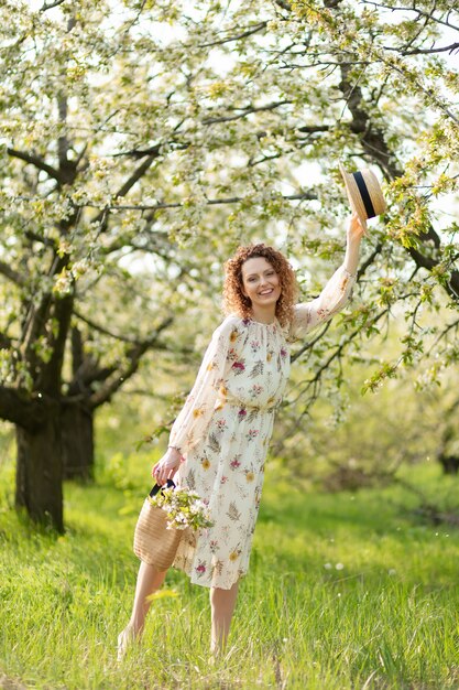 Una hermosa niña camina en un floreciente jardín de primavera. El concepto de unidad del hombre con la naturaleza.