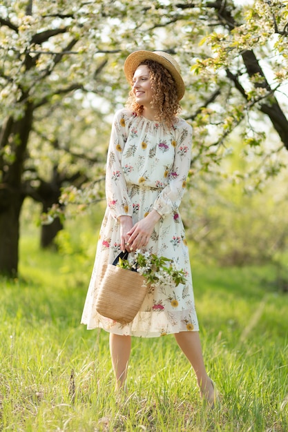 Una hermosa niña camina en un floreciente jardín de primavera