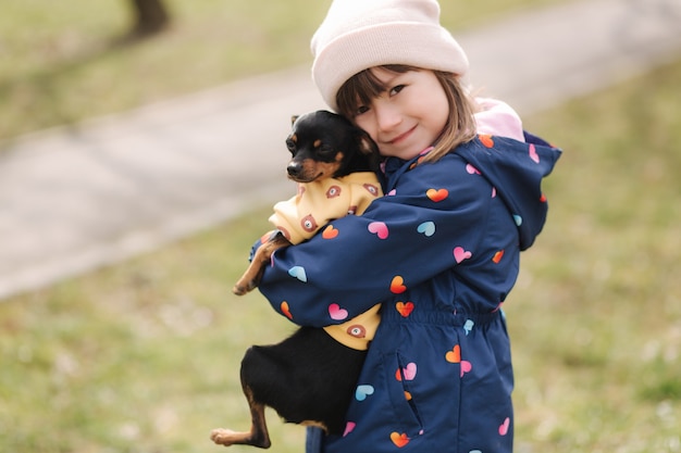 Hermosa niña caminar con lindo perro al aire libre niña de seis años abrazar a su mascota