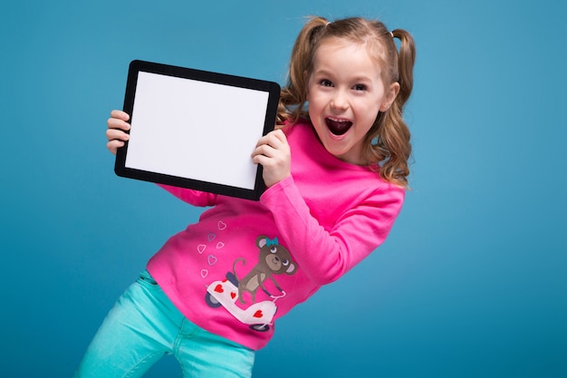 Hermosa niña en camisa rosa y pantalón azul con tableta vacía