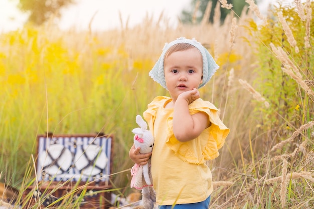 Una hermosa niña con una camiseta amarilla en un picnic en la naturaleza con un juguete en las manos