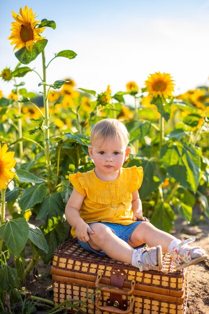 Hermosa niña en campo floreciente de girasol en verano