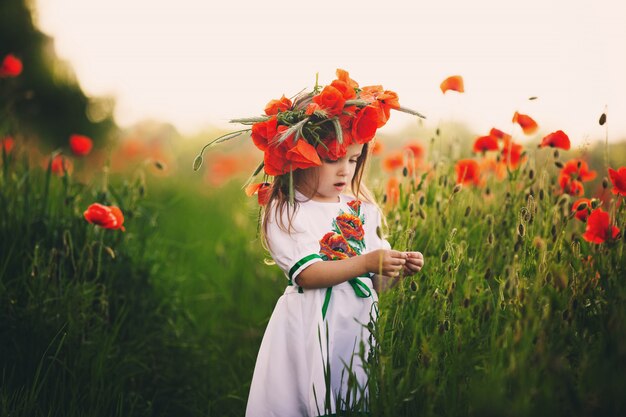 Hermosa niña en un campo de flores silvestres rojas