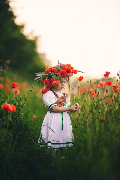 Foto hermosa niña en un campo de flores silvestres rojas