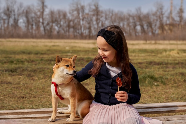 hermosa niña con un caramelo juega con un perro